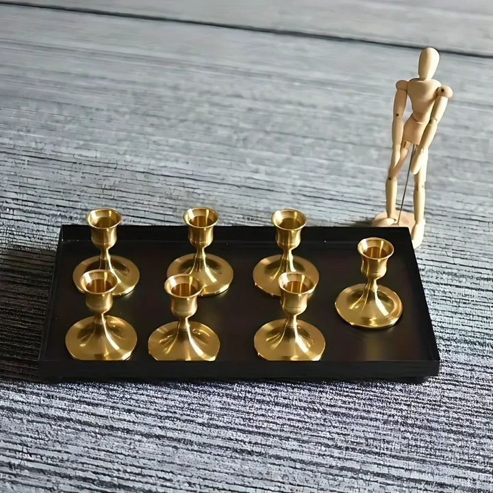 Set of two vintage brass taper candle holders on a black tray.