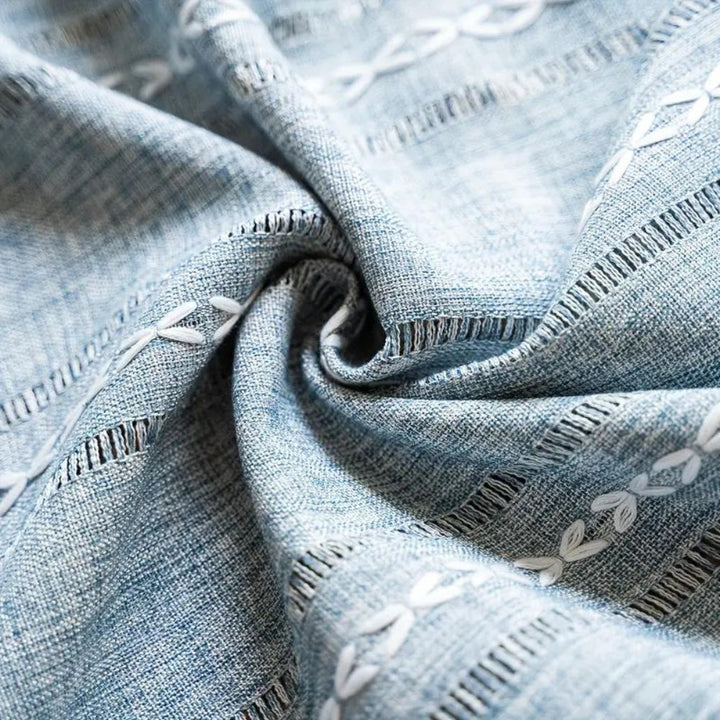 Close-up of blue and white embroidered cotton-linen fabric with a swirling texture.