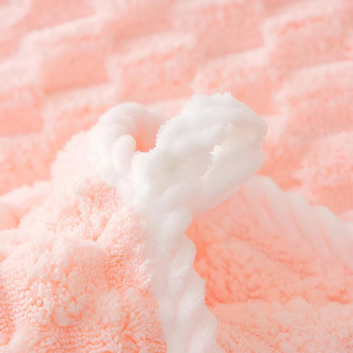 Close-up of a soft, pink fleece towel with a white textured edge.