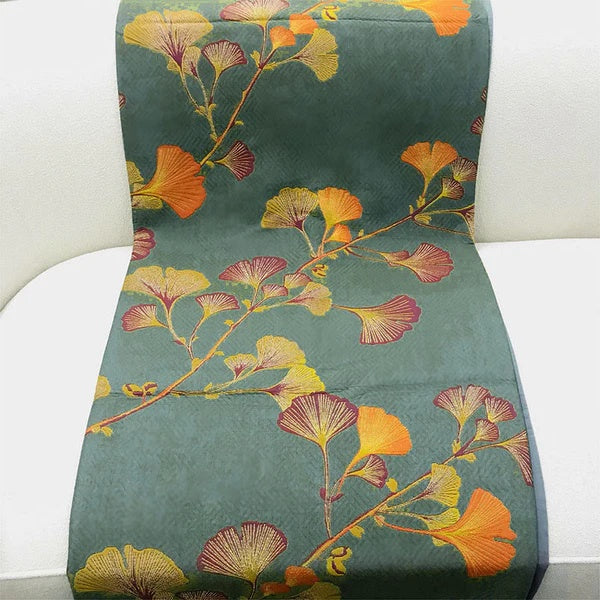Green reversible coverlet with a pattern of orange, yellow, and red ginkgo leaves.