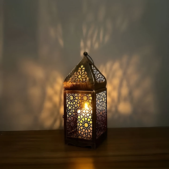 Antique iron candle holder with intricate Middle Eastern-inspired metalwork, casting a warm glow.