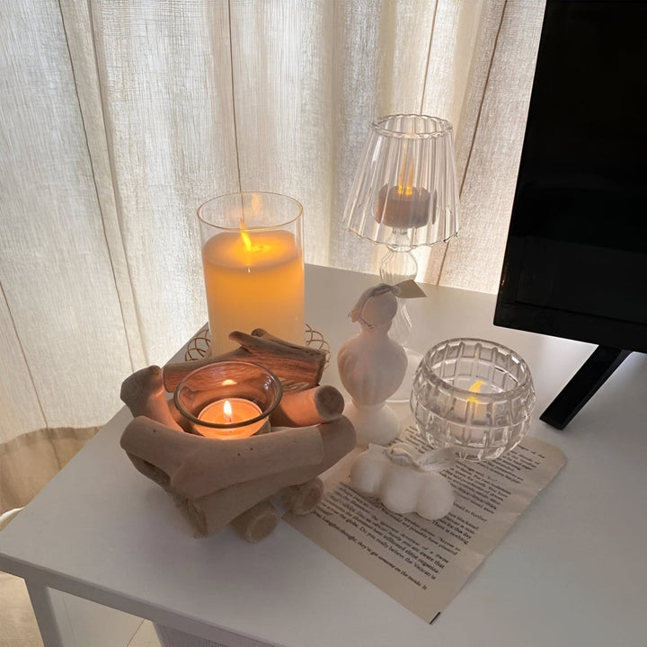 Driftwood tealight holder with a lit candle inside, surrounded by other candles and decor.