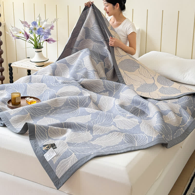 Mulberry Leaf Cotton Triple Gauze Blanket draped on a bed, showing a woman holding a corner.