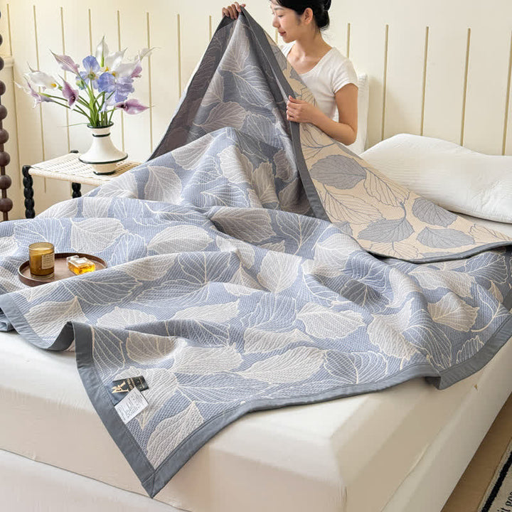 Mulberry Leaf Cotton Triple Gauze Blanket draped on a bed, showing a woman holding a corner.