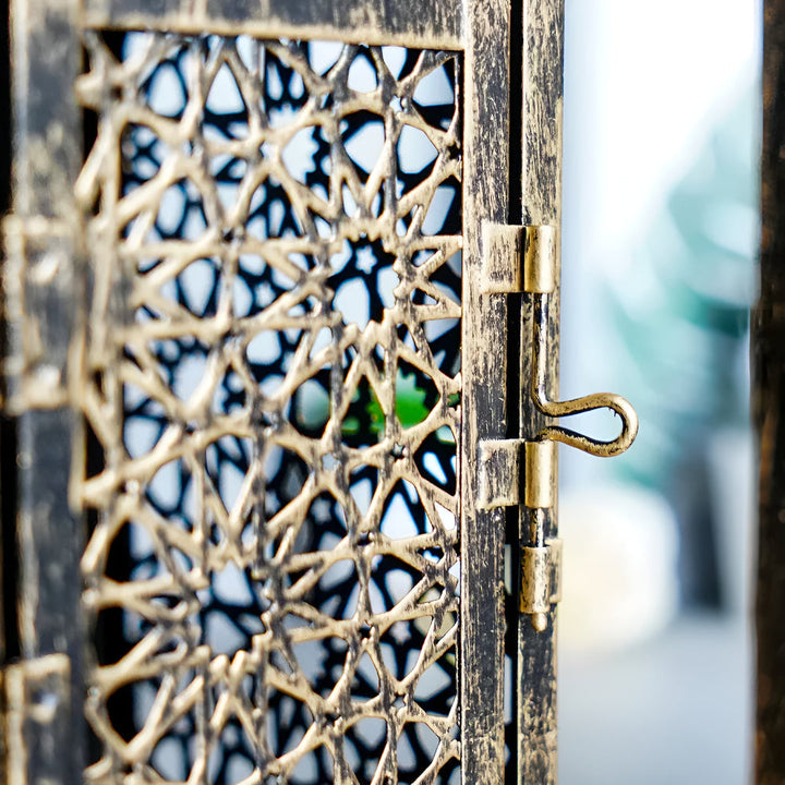 Close-up of an antique iron candle holder with intricate Middle Eastern-inspired metalwork and a latch.