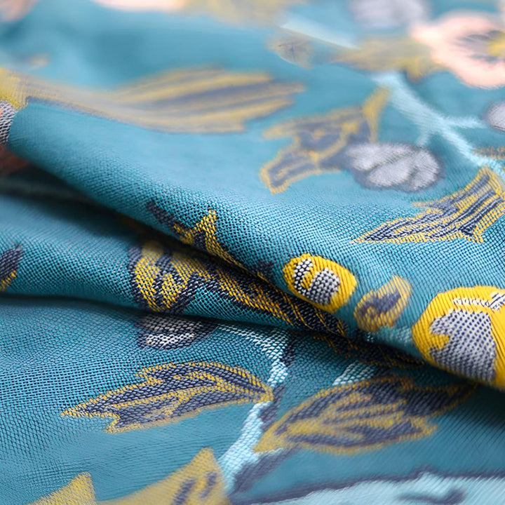 Close-up of a teal cotton bath towel featuring a reversible yellow and blue hibiscus floral pattern.