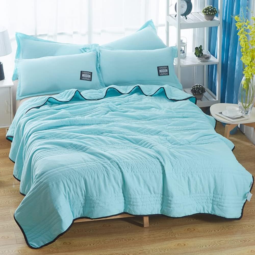Light blue EverChill Ice Cooling Blanket with black trim, folded on a bed with matching pillows.