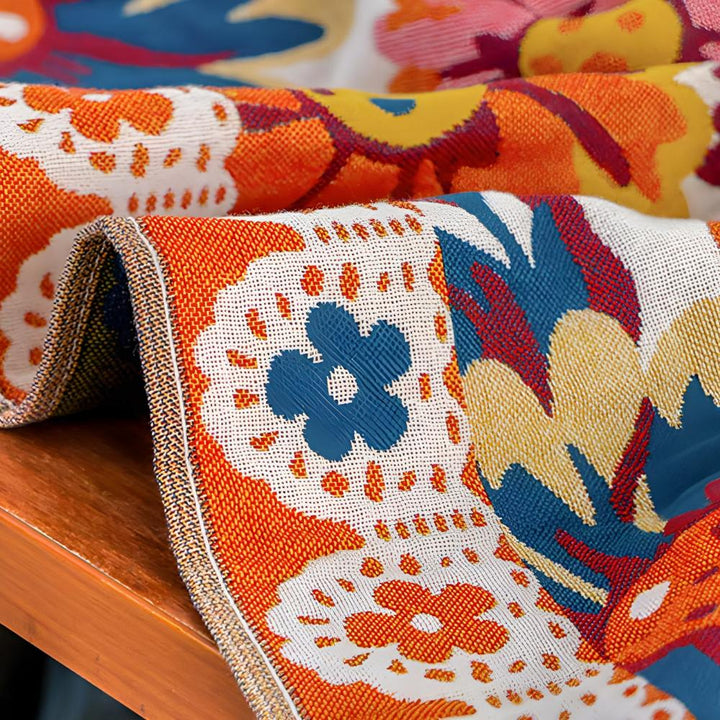 Close-up of a reversible cotton bath towel with a vibrant floral pattern in orange, blue, and yellow.
