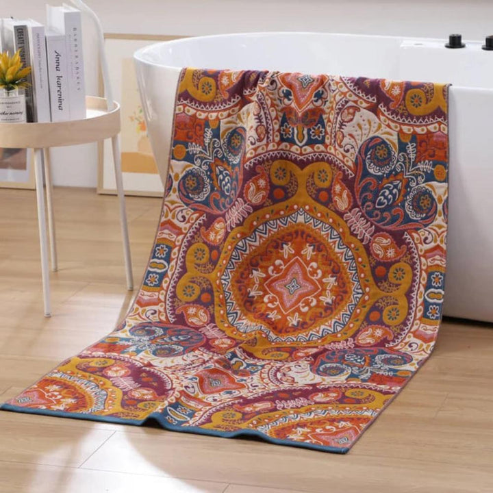 A colorful, boho-patterned cotton bath towel draped over a white bathtub.