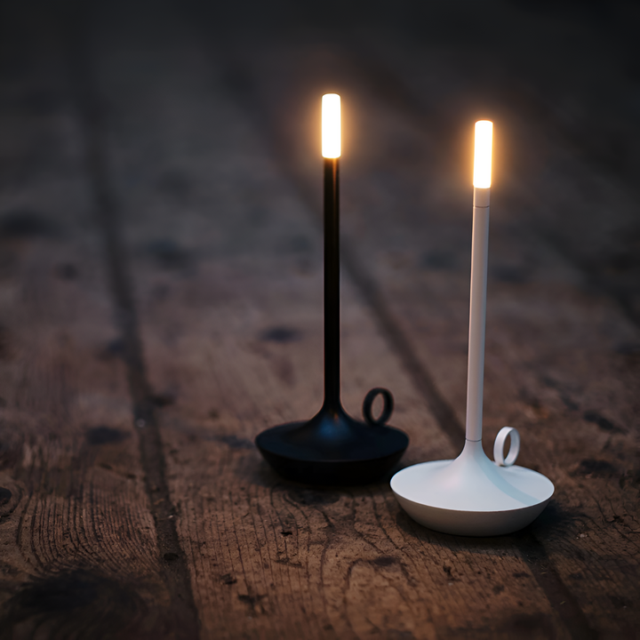 Two portable aluminum table lamps, one black and one white, with warm LED lights, on a wooden surface.