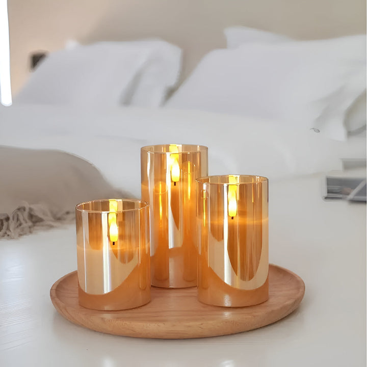 Three amber glass flameless candles with 3D LED flames on a wooden tray.
