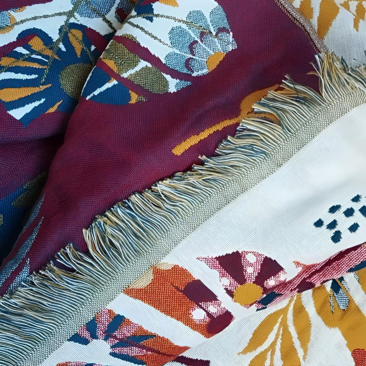 Close-up of a reversible cotton bath towel with a burgundy and cream floral pattern and fringe.