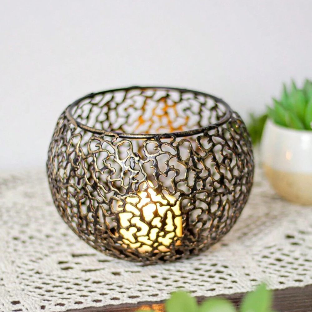 Geometric iron tealight holder with a sphere design and a lit candle inside.