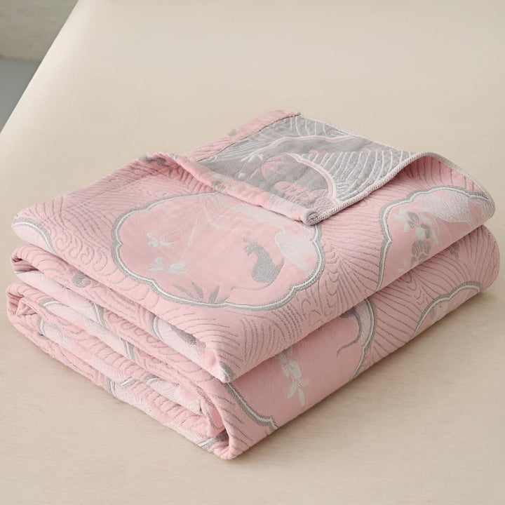 Folded pink blanket with a grey and white floral pattern.
