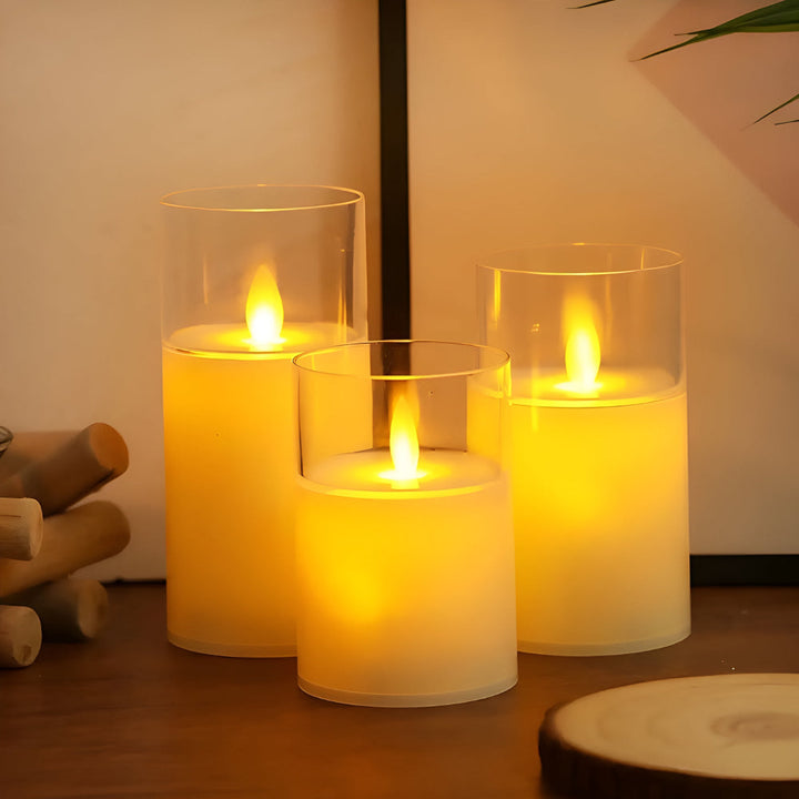 Three flameless LED candles with realistic 3D flames in glass cylinders on a wooden surface.