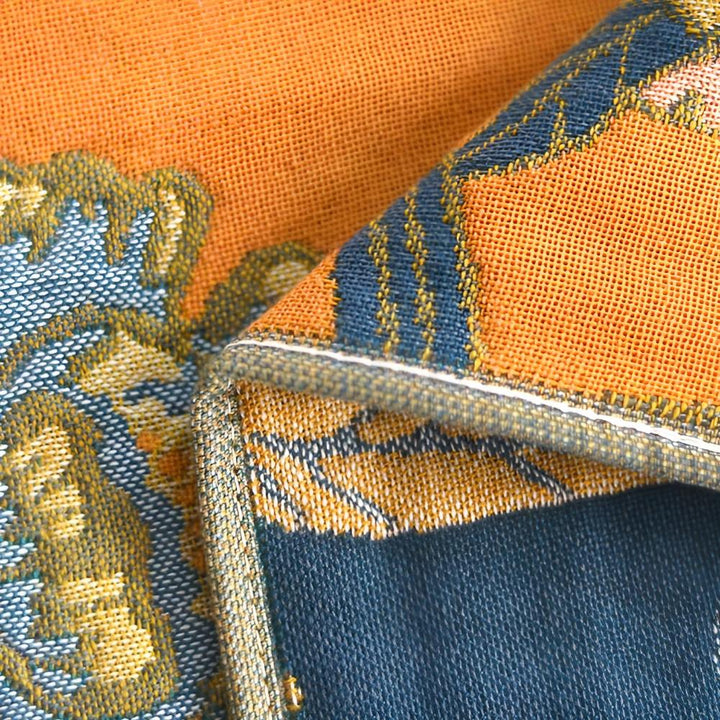 Close-up of a reversible cotton bath towel with orange and blue hibiscus pattern.
