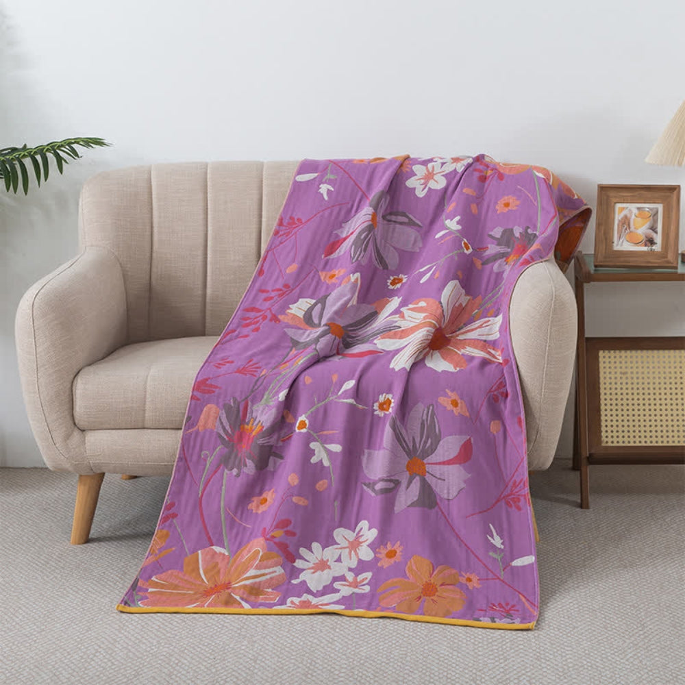 Cotton gauze bath towel with a floral pattern on a purple background, draped over a chair.