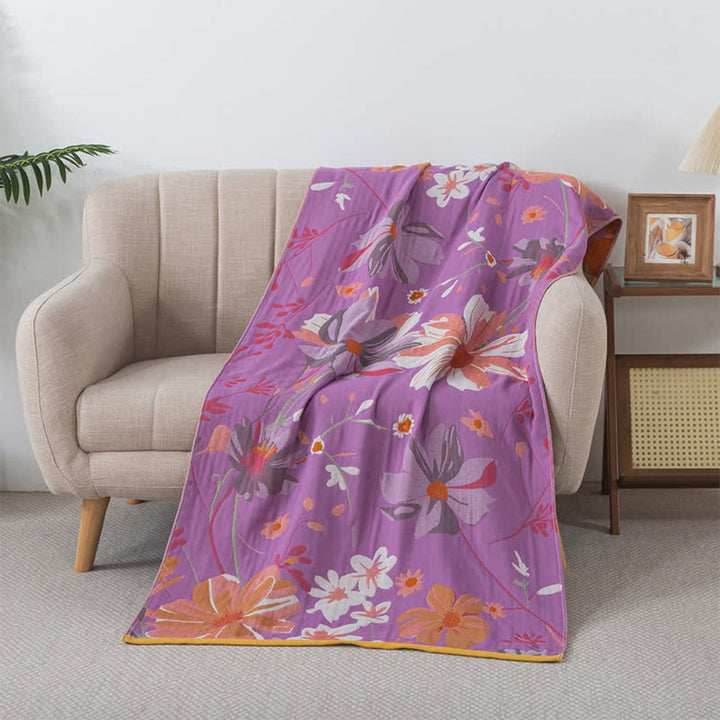 Cotton gauze bath towel with a floral pattern on a purple background, draped over a chair.