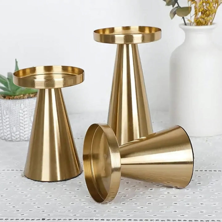 Set of three artisan brass candle holders in varying sizes, with a modern conical design.