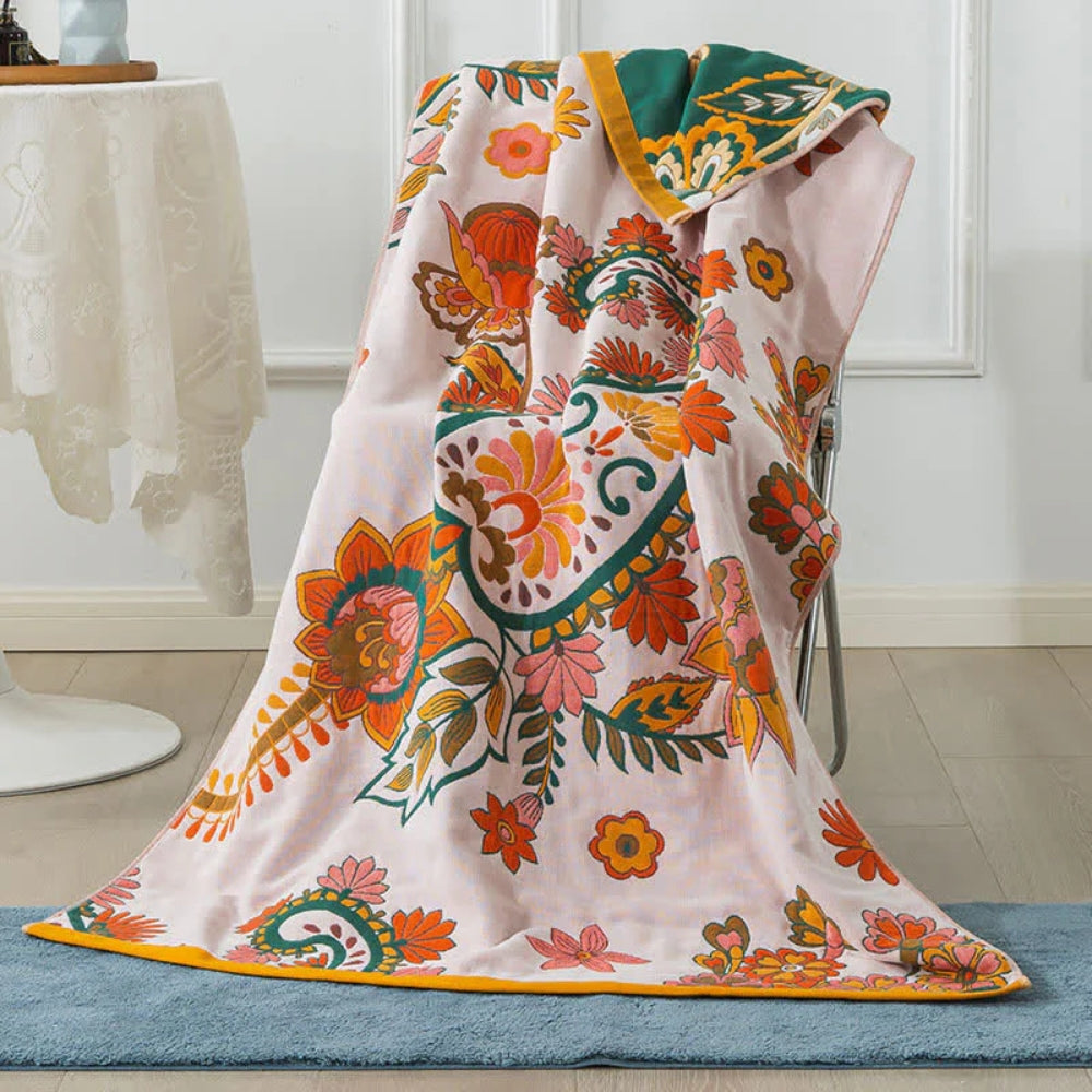 Pink cotton gauze bath towel with a vibrant floral pattern in orange, green, and yellow.