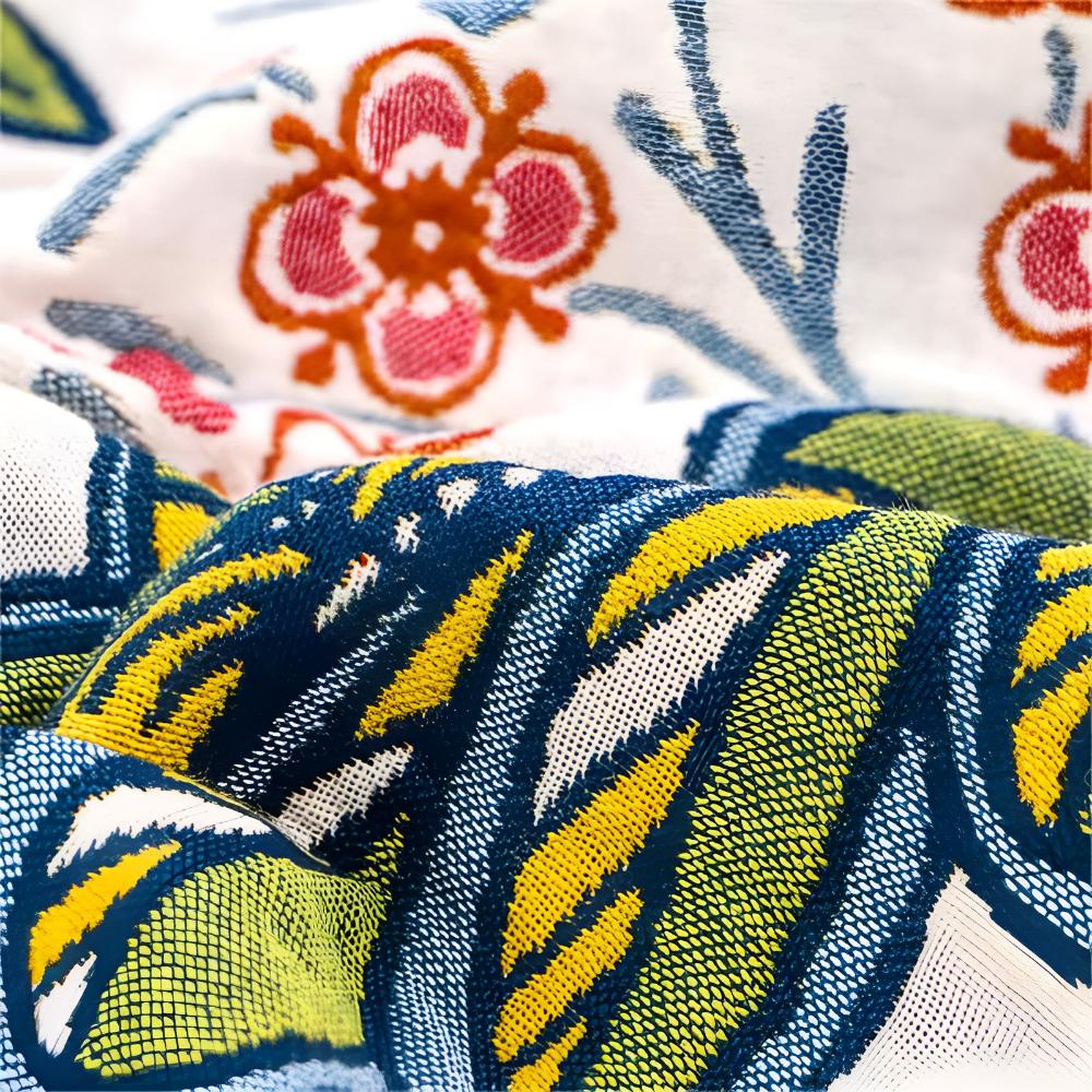 Close-up of a reversible cotton bath towel with a vibrant blue and yellow abstract pattern and a floral print.