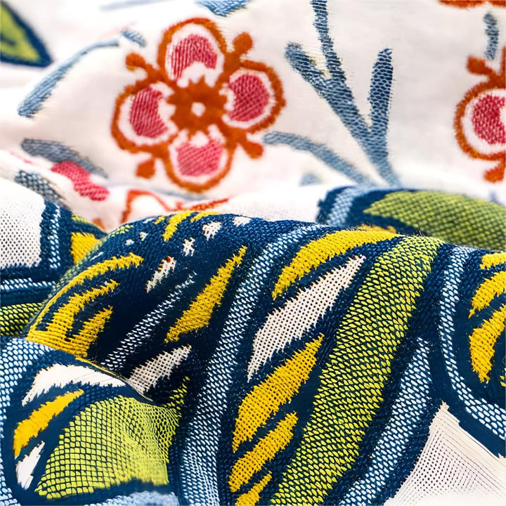 Close-up of a reversible cotton bath towel with a vibrant blue and yellow abstract pattern and a floral print.