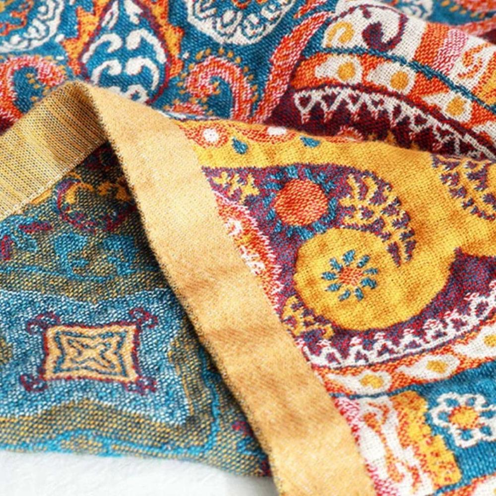 Close-up of a colorful boho-patterned cotton bath towel with geometric and floral designs in blue, yellow, and orange.