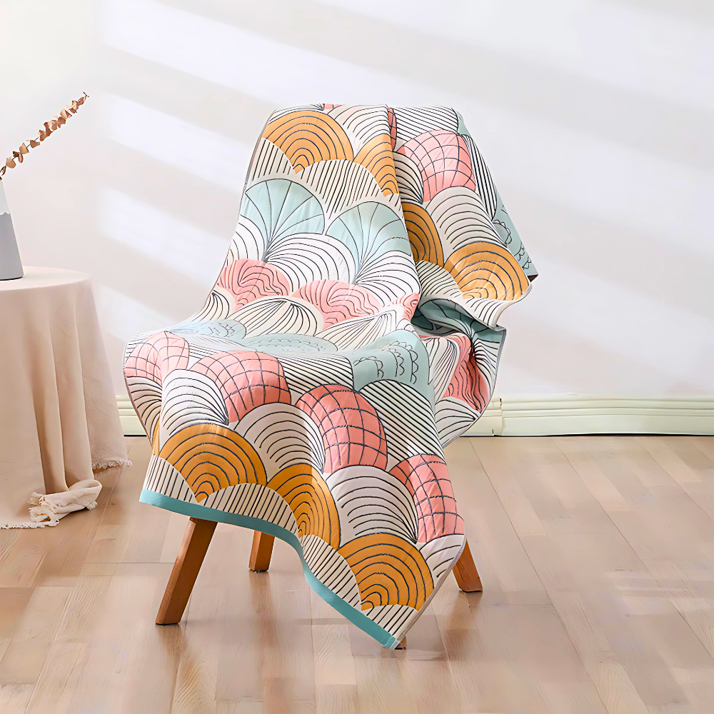 A colorful cotton bath towel with a shell-like pattern draped over a wooden chair.