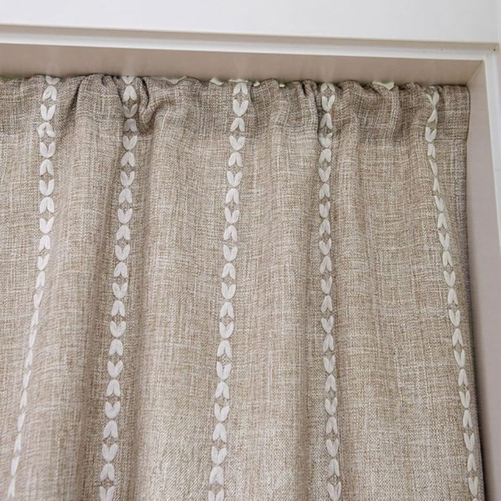 Beige linen-look curtain with vertical white embroidered leaf pattern.