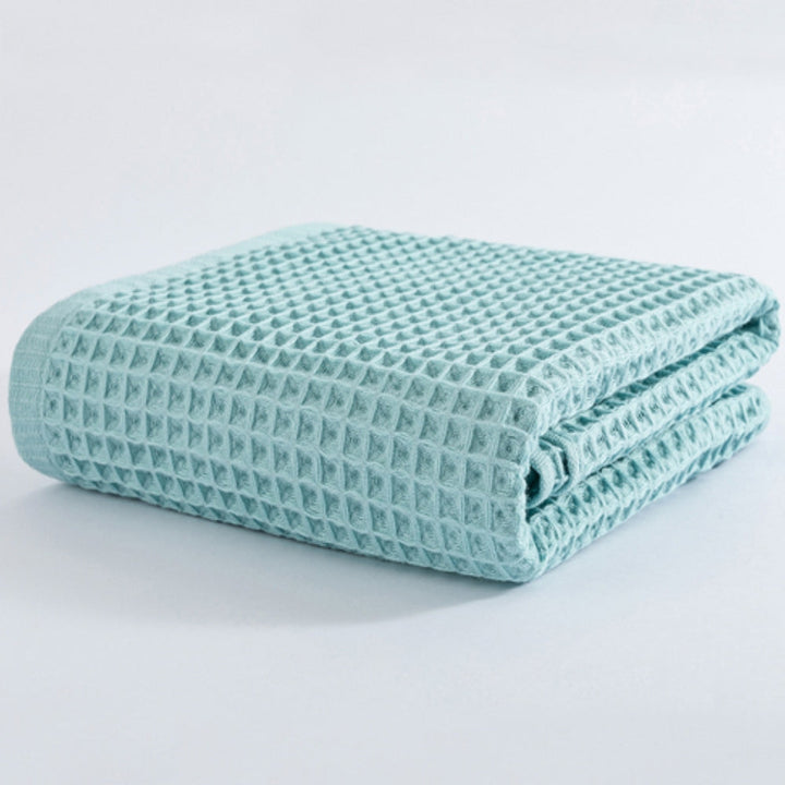 Light blue cotton waffle bath towel folded on a white background.