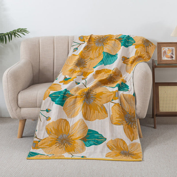 A soft, 100% cotton bath towel with a large yellow floral print and teal leaves, draped over a light-colored armchair.