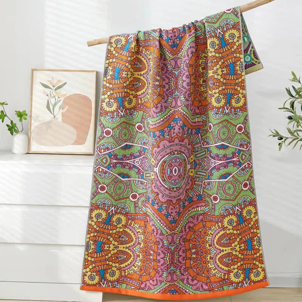 Cotton gauze bath towel with a vibrant, intricate Moroccan-inspired mandala pattern in orange, green, pink, and blue.