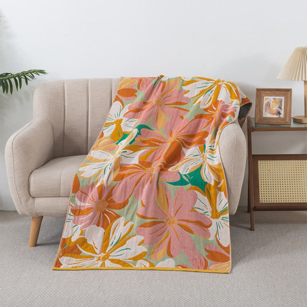 Cotton gauze bath towel with a large floral print in pink, orange, and yellow on a light green background.