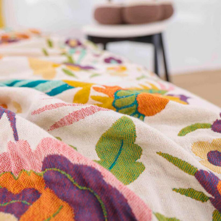 A soft coverlet with a colorful floral pattern in shades of pink, orange, green, and blue.