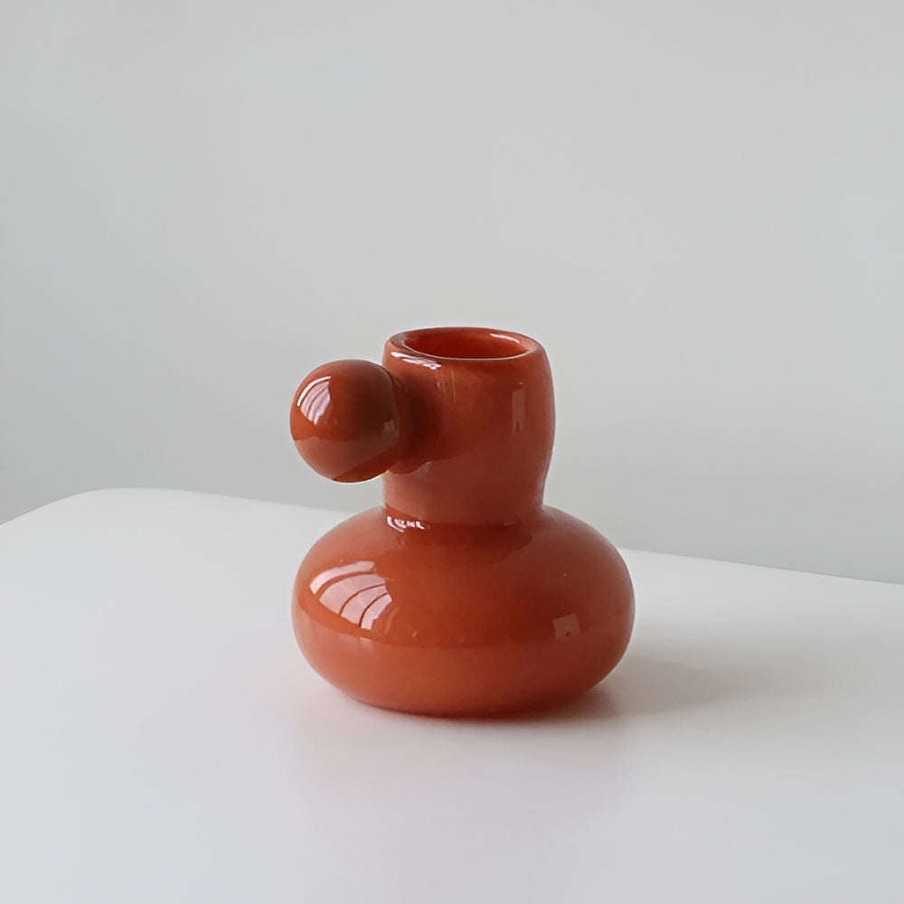 Orange glass candle holder with a round base and a ball accent on the side.