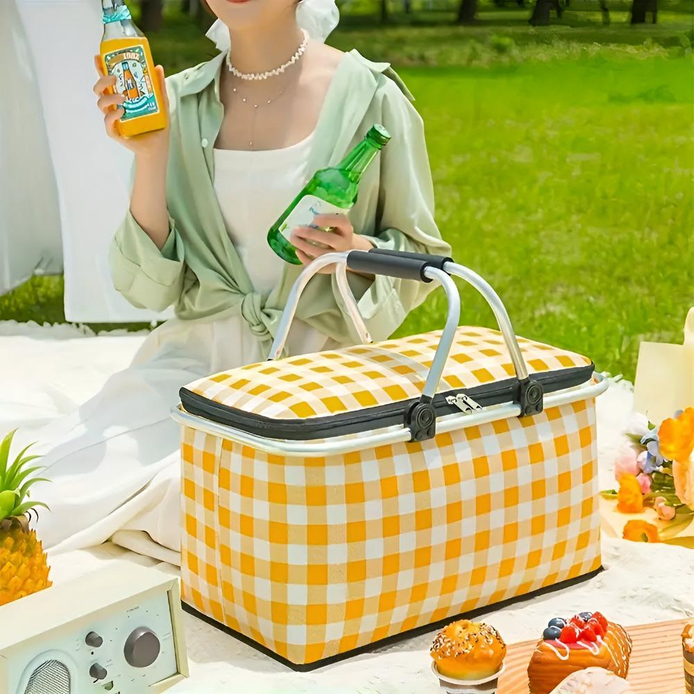 Yellow and white checkered picnic basket with a woman holding drinks in the background.