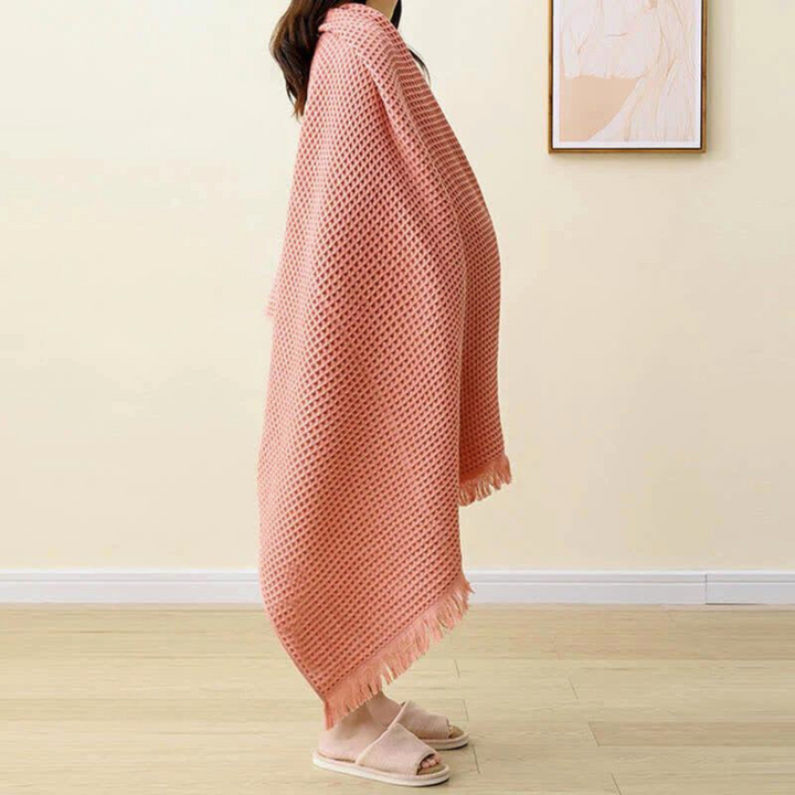 Woman wearing a pink waffle-weave cotton towel like a shawl, with fringe detail.