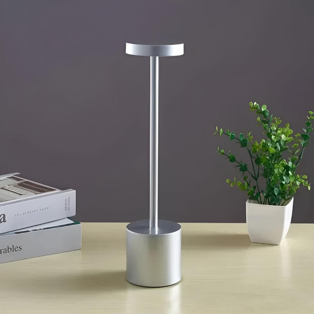 Silver cordless table lamp with a cylindrical base and a slender stem topped with a circular light.