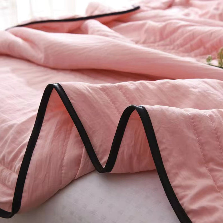 Close-up of a pink EverChill cooling blanket with black trim, showing its quilted texture.