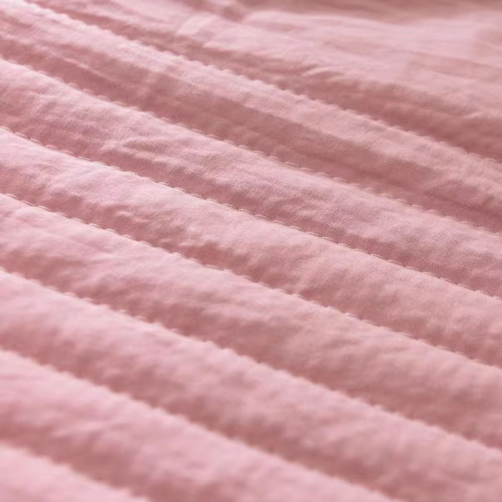 Close-up of a pink quilted cooling blanket with horizontal stitching.