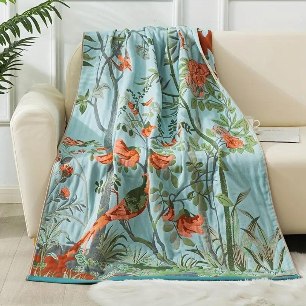 Light blue cotton bath towel with a vibrant bird and floral leaf pattern.