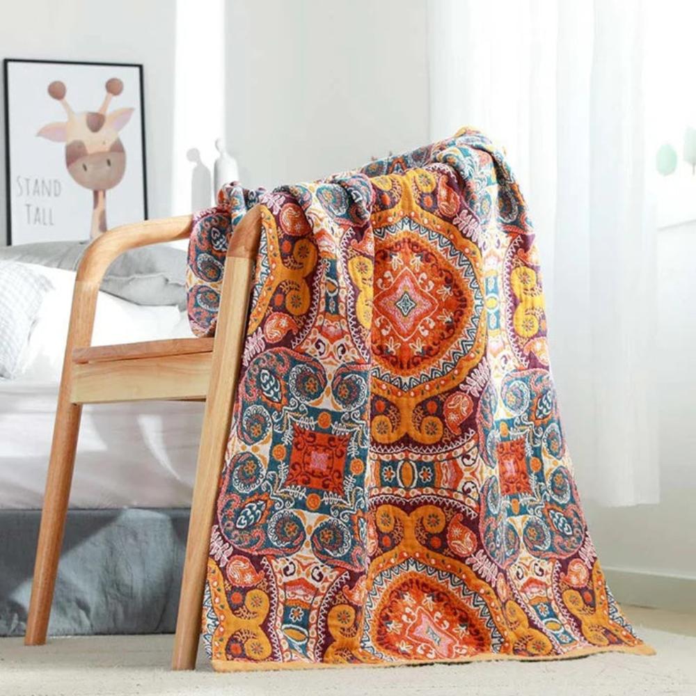A colorful boho-patterned cotton bath towel draped over a wooden chair.