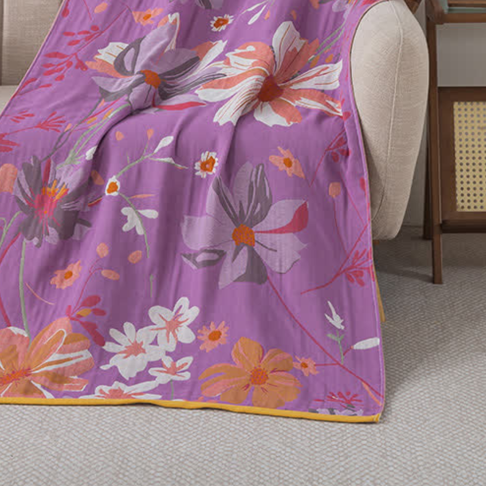 Purple cotton gauze bath towel with a vintage wildflower pattern in pink, orange, and white.