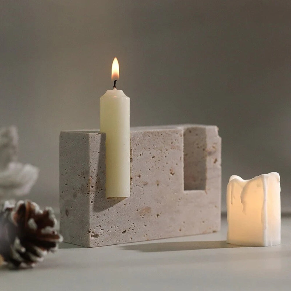 Travertine taper candle holder with one lit candle and one LED candle.