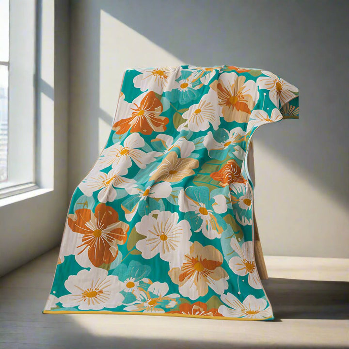 Cotton gauze bath towel with a bright teal background and a pattern of white, orange, and tan flowers.