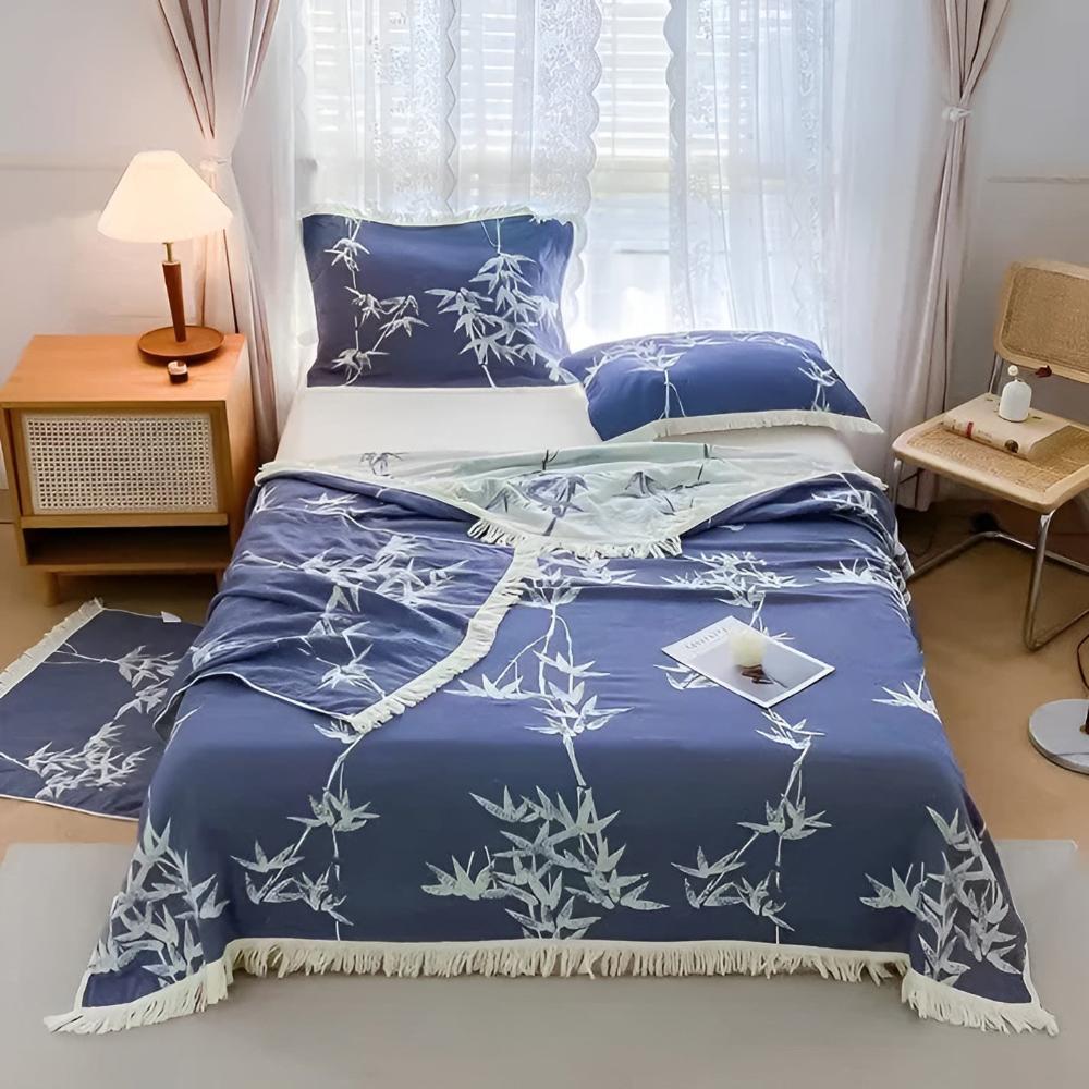 Blue bamboo cotton reversible jacquard throw with white bamboo pattern and fringe on a bed.