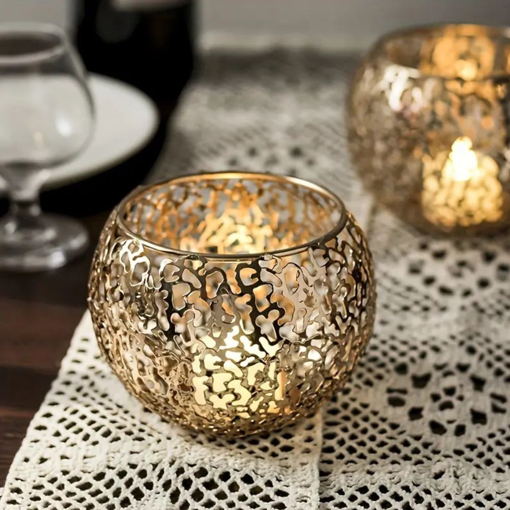 Gold geometric iron tealight holder with a sphere design, casting intricate shadows.
