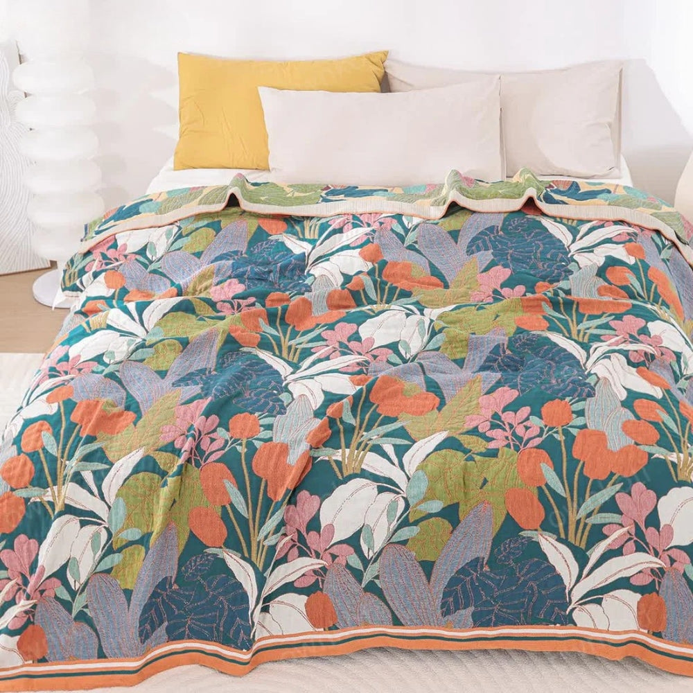 A cotton gauze blanket with a vibrant floral pattern in shades of teal, orange, pink, and white.