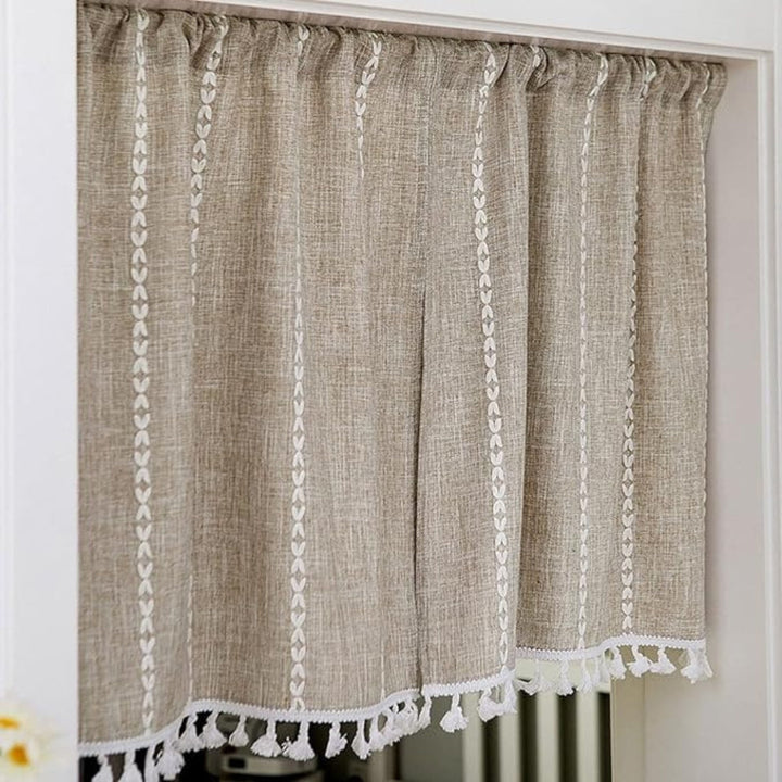 Beige linen-blend kitchen curtain with white embroidered vertical stripes and tassel trim.