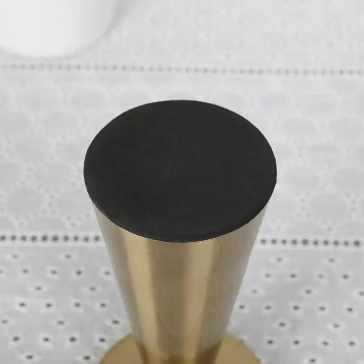 Top view of a brass candle holder with a black rubber stopper.
